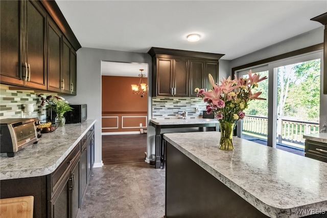 591 Girdle Rd, Elma, NY 14052 - kitchen with backsplash, light countertops, a chandelier, a decorative wall, and dark brown cabinetry