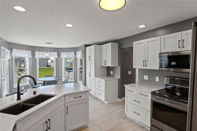 1030 Whistlers Cove Ln, Greece, NY 14612 - kitchen featuring stainless steel appliances, a sink, white cabinets, hanging light fixtures, and recessed lighting