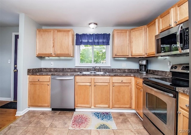 106 Peterson Dr, Camillus, NY 13031 - kitchen with stainless steel appliances, a sink, dark countertops, light brown cabinetry, and baseboards