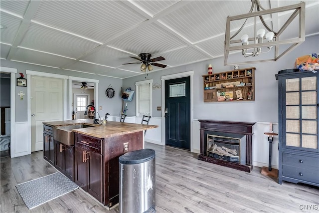 44191 Lime St, Wilna, NY 13665 - kitchen with ceiling fan, a sink, light wood-style floors, a kitchen island with sink, and a glass covered fireplace