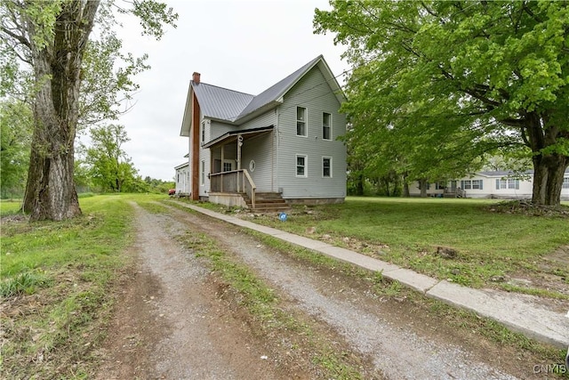 44191 Lime St, Wilna, NY 13665 - view of front of home featuring a chimney, dirt driveway, a front yard, covered porch, and metal roof