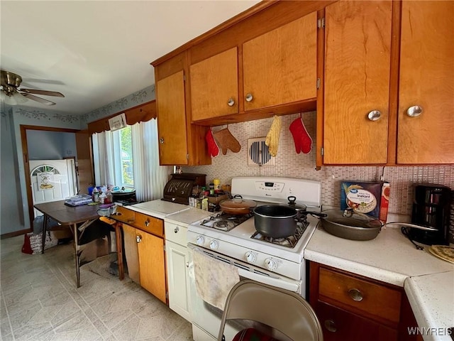 815 91st St, Niagara Falls, NY 14304 - kitchen with white gas range oven, light countertops, brown cabinets, and a ceiling fan