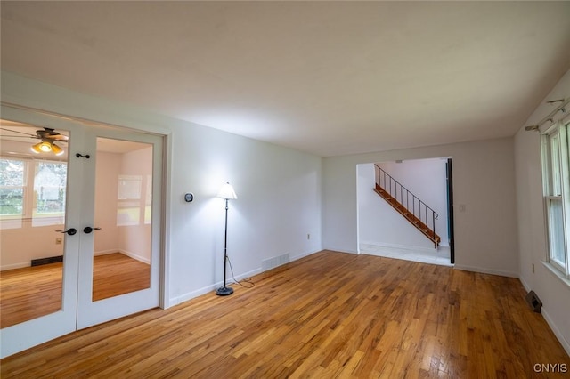 7634 Anne Ter, Clay, NY 13212 - unfurnished room featuring light wood-style flooring, ceiling fan, stairs, french doors, and baseboards