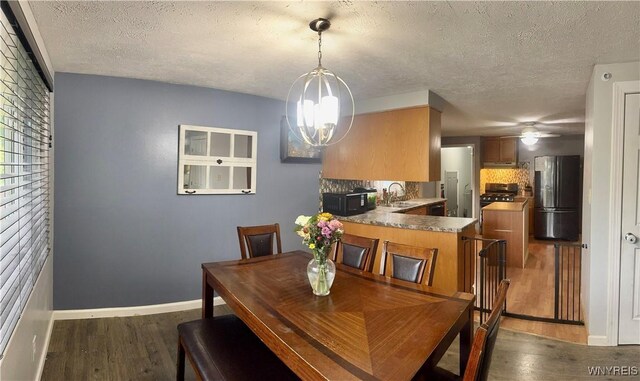 9357 Steffi Dr, Evans, NY 14006 - dining room with dark wood-type flooring, a chandelier, a textured ceiling, baseboards, and a ceiling fan