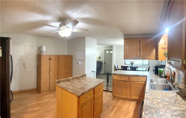 9357 Steffi Dr, Evans, NY 14006 - kitchen featuring freestanding refrigerator, a sink, light wood-type flooring, a textured ceiling, and a center island