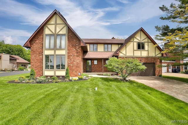 2227 W River Rd, Grand Island, NY 14072 - tudor-style house with a garage, driveway, a front yard, stucco siding, and brick siding