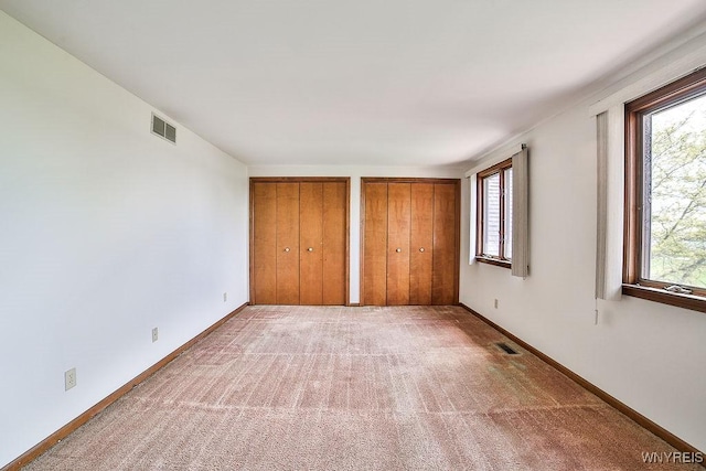 2227 W River Rd, Grand Island, NY 14072 - unfurnished bedroom with multiple closets, light colored carpet, and baseboards