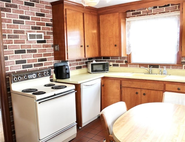 311 N Rogers Pkwy W, Irondequoit, NY 14617 - kitchen with white appliances, a sink, light countertops, dark tile patterned floors, and brown cabinets