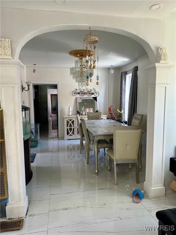 512 Sherman St, Buffalo, NY 14211 - dining space featuring arched walkways, light marble finish flooring, ornate columns, and a chandelier