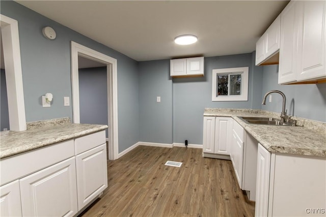 118 Leray St, Le Ray, NY 13612 - kitchen featuring a sink, light wood-type flooring, white cabinets, light countertops, and baseboards