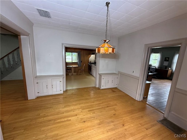 26 Farnham St, Cazenovia, NY 13035 - unfurnished dining area with light wood-style floors, plenty of natural light, stairs, and wainscoting