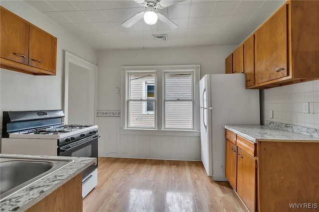 151 Edson St, West Seneca, NY 14210 - kitchen featuring range with gas cooktop, freestanding refrigerator, brown cabinets, light wood-type flooring, and a ceiling fan