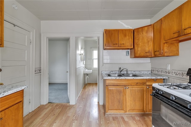 151 Edson St, West Seneca, NY 14210 - kitchen featuring gas range, a sink, light countertops, light wood-type flooring, and brown cabinetry