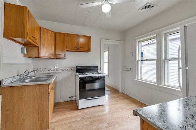 151 Edson St, West Seneca, NY 14210 - kitchen featuring range with gas stovetop, brown cabinetry, a ceiling fan, light wood-style floors, and a sink