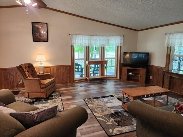 3483 First Fork Rd, Grove Twp, PA 15861 - living room featuring wainscoting, a textured ceiling, wooden walls, lofted ceiling, and wood finished floors