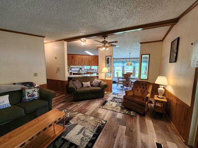 3483 First Fork Rd, Grove Twp, PA 15861 - living area with wooden walls, a textured ceiling, wainscoting, crown molding, and wood finished floors