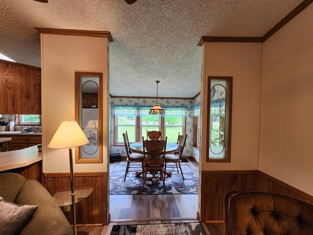 3483 First Fork Rd, Grove Twp, PA 15861 - dining space with a textured ceiling, crown molding, wood walls, wainscoting, and wood finished floors