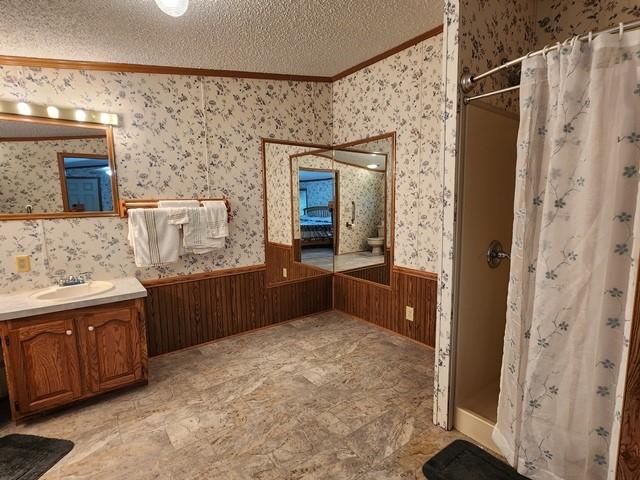 3483 First Fork Rd, Grove Twp, PA 15861 - full bath featuring ornamental molding, a wainscoted wall, a stall shower, vanity, and a textured ceiling