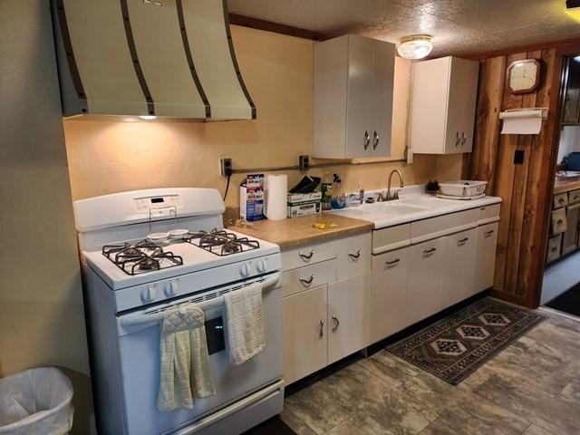 3483 First Fork Rd, Grove Twp, PA 15861 - kitchen with white range with gas stovetop, white cabinets, light countertops, and ventilation hood