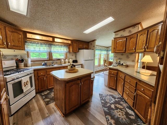 3483 First Fork Rd, Grove Twp, PA 15861 - kitchen featuring white appliances, wood finished floors, a sink, a textured ceiling, and a kitchen island