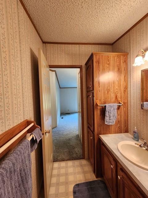 3483 First Fork Rd, Grove Twp, PA 15861 - bathroom featuring a textured ceiling, crown molding, wallpapered walls, tile patterned floors, and vanity