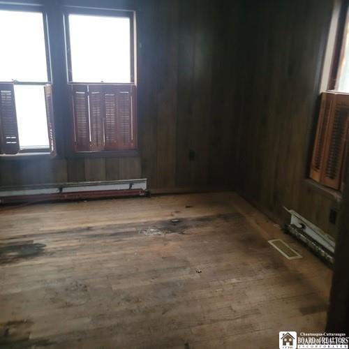 206 W Green St, Olean-City, NY 14760 - empty room with wood finished floors, plenty of natural light, and a baseboard radiator