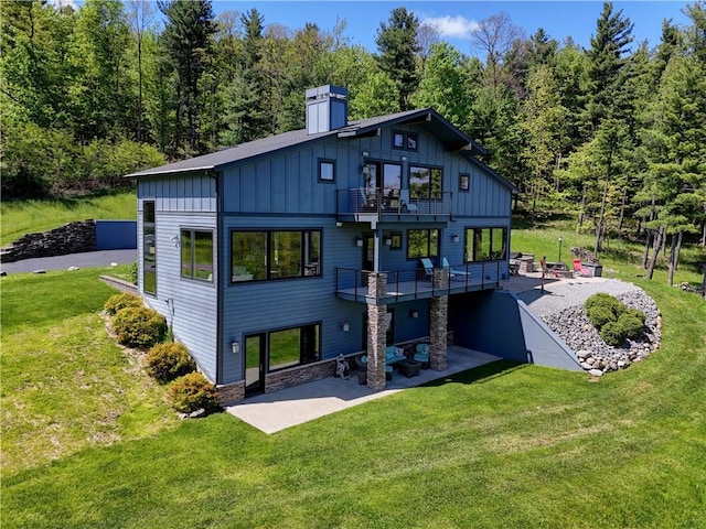 8763 Greyton H Taylor Memorial Dr, Urbana, NY 14840 - back of property featuring board and batten siding, a balcony, a patio area, a chimney, and a yard