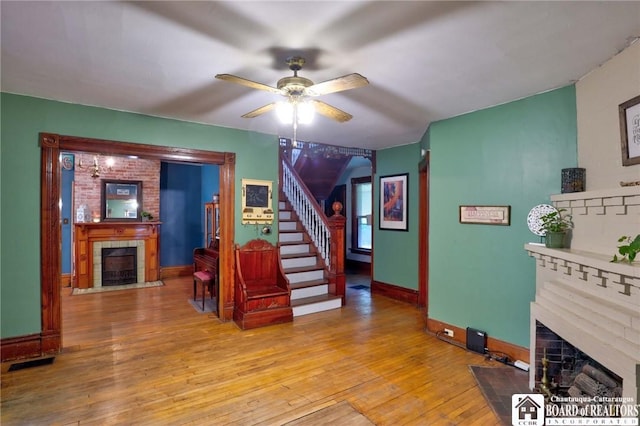 25 Academy St, Westfield, NY 14787 - living area featuring a fireplace with flush hearth, light wood-style floors, a ceiling fan, baseboards, and stairs