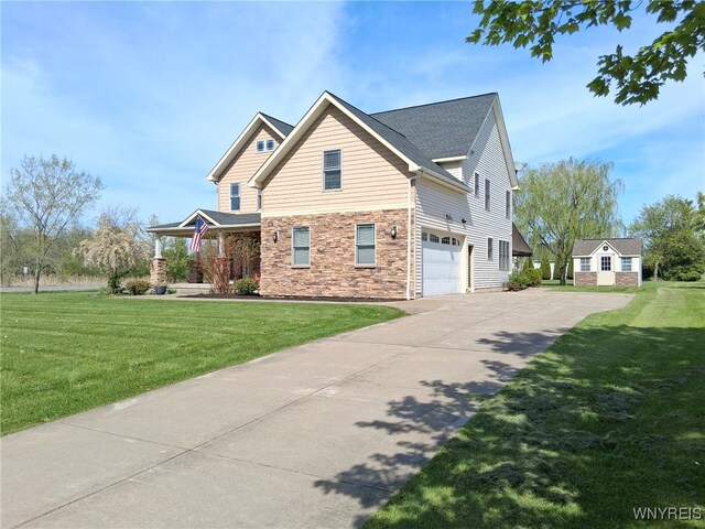 65 Islewoods, Grand Island, NY 14072 - view of home's exterior featuring a garage, concrete driveway, stone siding, and a yard