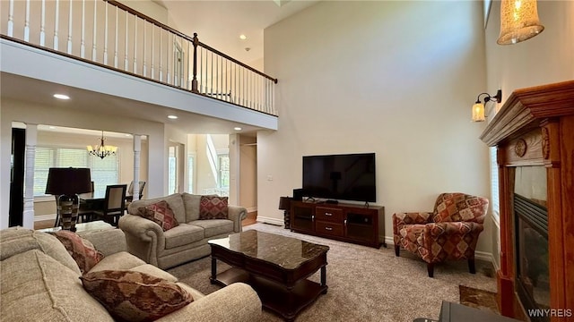 65 Islewoods, Grand Island, NY 14072 - carpeted living room featuring a fireplace with flush hearth, a chandelier, a high ceiling, baseboards, and plenty of natural light