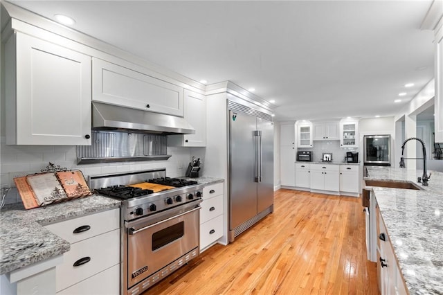 1 Creekside Ln, Pittsford, NY 14618 - kitchen with high quality appliances, under cabinet range hood, a sink, decorative backsplash, and light wood-type flooring