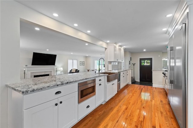 1 Creekside Ln, Pittsford, NY 14618 - kitchen with a sink, a peninsula, built in appliances, white cabinets, and light wood-style floors