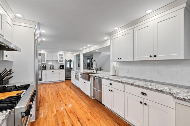 1 Creekside Ln, Pittsford, NY 14618 - kitchen with appliances with stainless steel finishes, beverage cooler, wall chimney range hood, a sink, and white cabinets