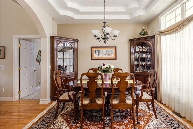 31 Hunters Run, Horseheads, NY 14845 - dining room featuring arched walkways, light wood-style floors, a chandelier, a raised ceiling, and baseboards
