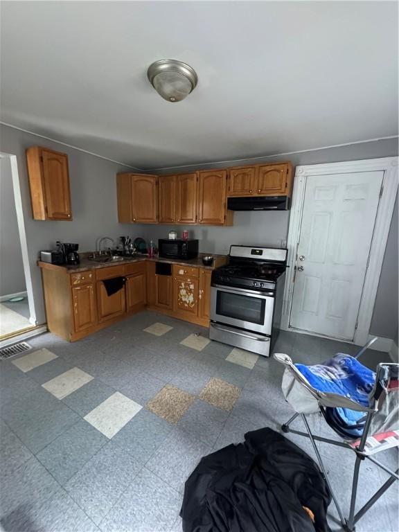 127 Maryland St, Rochester, NY 14613 - kitchen with stainless steel gas range, under cabinet range hood, black microwave, and brown cabinetry