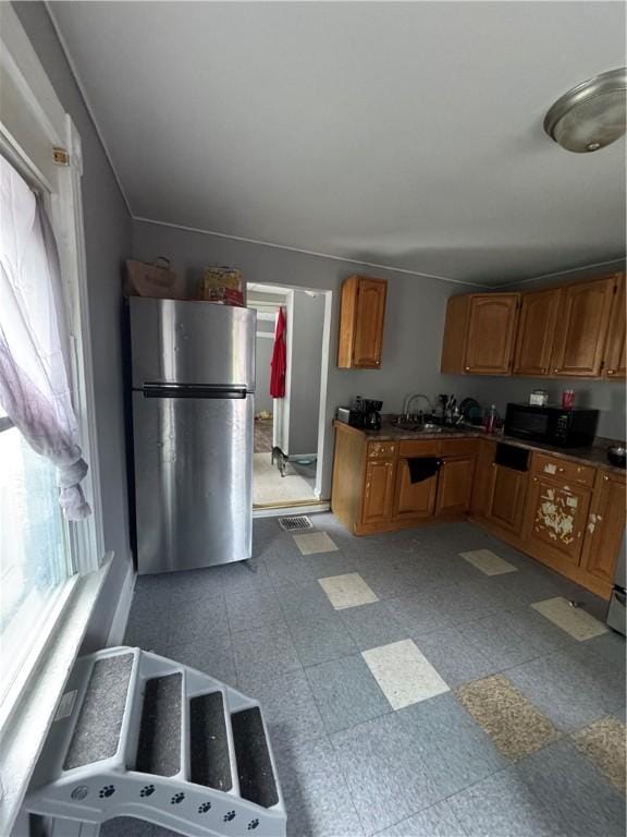 127 Maryland St, Rochester, NY 14613 - kitchen featuring freestanding refrigerator, black microwave, brown cabinetry, and dark countertops