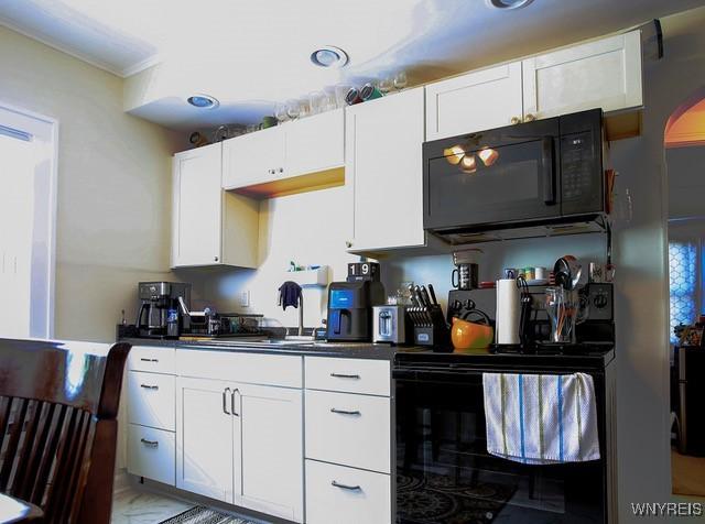 938 Ridge Rd, Lackawanna, NY 14218 - kitchen featuring black appliances, dark countertops, white cabinetry, and crown molding
