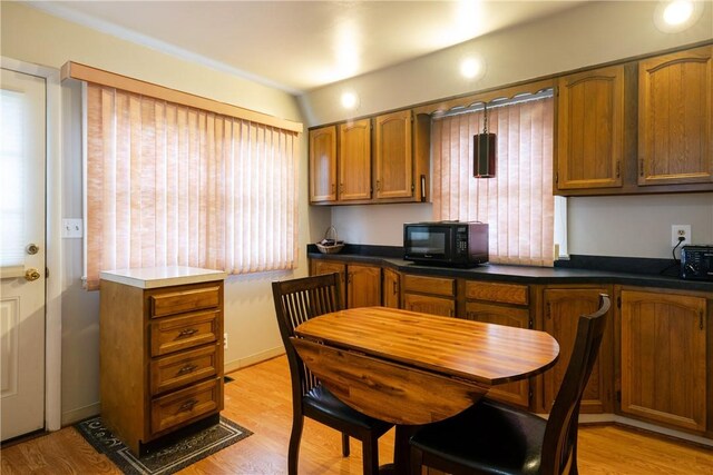 182 E Pulteney St, Corning City, NY 14830 - kitchen with black microwave, brown cabinets, light wood-style flooring, and dark countertops