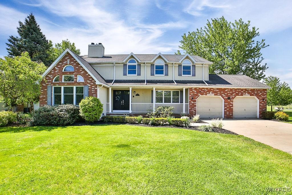 30 River Oaks Dr, Grand Island, NY 14072 - traditional-style house with an attached garage, a chimney, a front yard, a porch, and driveway