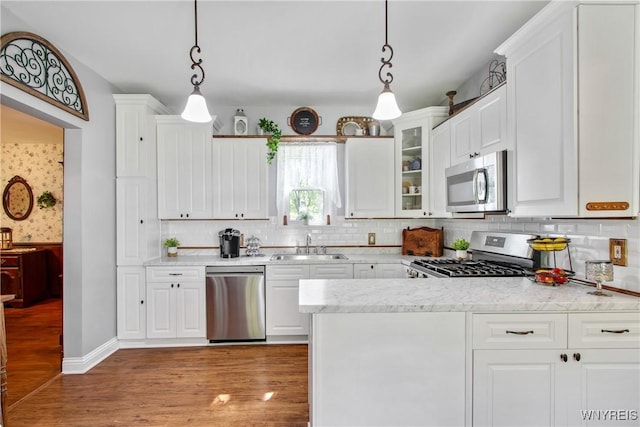 7263 Quaker Rd, Orchard Park, NY 14127 - kitchen featuring stainless steel appliances, a sink, white cabinets, light wood-style flooring, and backsplash