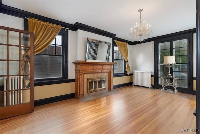 2884 Main St, Buffalo, NY 14214 - unfurnished living room with radiator heating unit, ornamental molding, a chandelier, wood finished floors, and baseboards