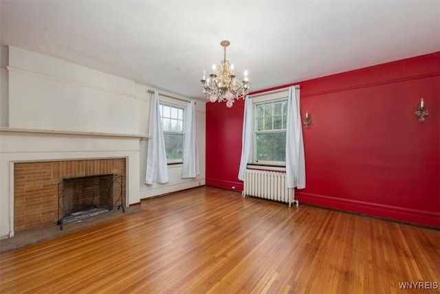 2884 Main St, Buffalo, NY 14214 - unfurnished living room featuring radiator, a baseboard radiator, wood finished floors, a chandelier, and a brick fireplace