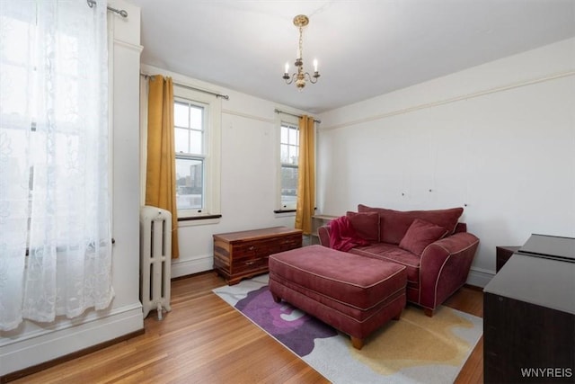2884 Main St, Buffalo, NY 14214 - living area featuring radiator heating unit, a chandelier, light wood-style flooring, and baseboards