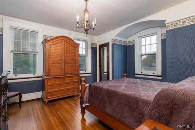 2884 Main St, Buffalo, NY 14214 - bedroom with a chandelier, wood finished floors, arched walkways, and baseboards