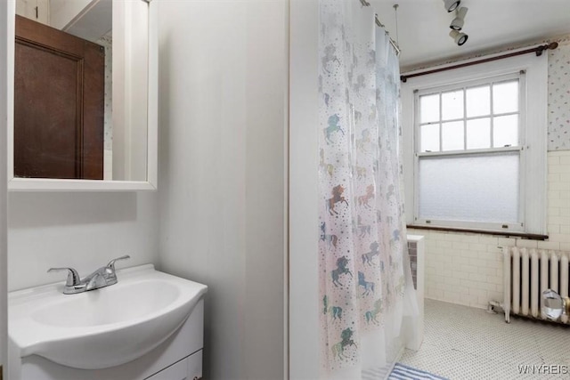 2884 Main St, Buffalo, NY 14214 - full bath with radiator heating unit, vanity, tile walls, a shower with curtain, and tile patterned flooring