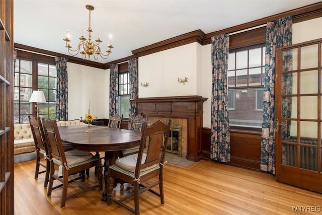 2884 Main St, Buffalo, NY 14214 - dining space with crown molding, a chandelier, plenty of natural light, light wood-type flooring, and a wainscoted wall