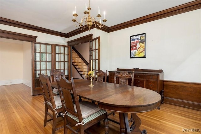 2884 Main St, Buffalo, NY 14214 - dining room featuring a chandelier, light wood-style flooring, crown molding, stairs, and baseboards