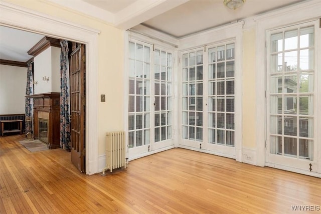 2884 Main St, Buffalo, NY 14214 - interior space featuring radiator heating unit, wood finished floors, crown molding, and a fireplace with flush hearth