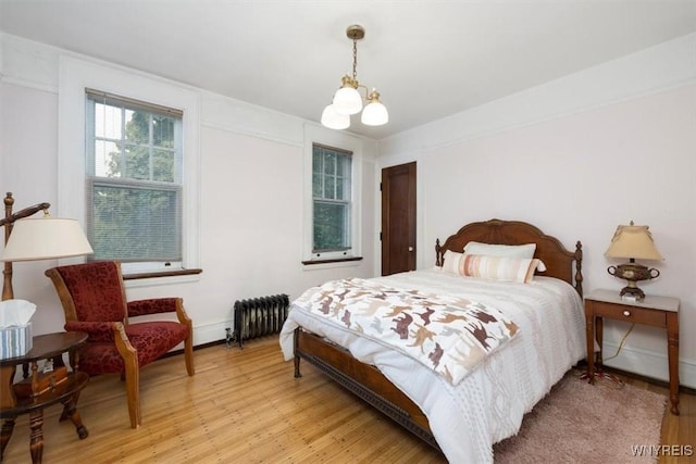 2884 Main St, Buffalo, NY 14214 - bedroom with light wood finished floors, radiator, baseboards, and a chandelier