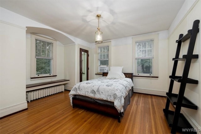 2884 Main St, Buffalo, NY 14214 - bedroom with radiator heating unit, wood finished floors, arched walkways, and baseboards